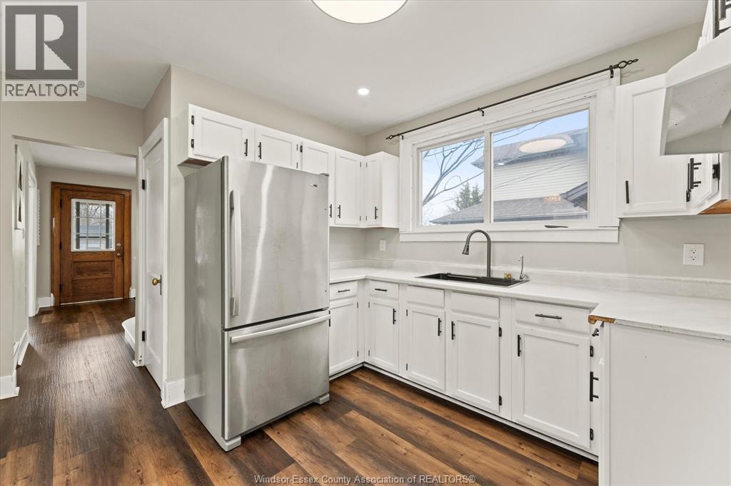 A kitchen with white cabinets and a stainless steel refrigerator.