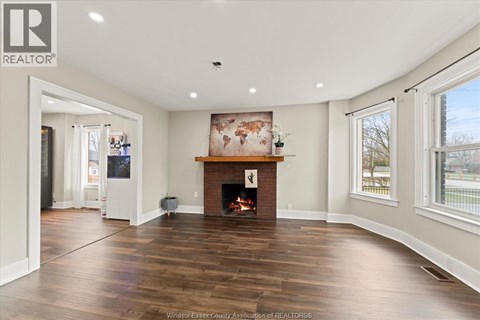 A spacious living room with a fireplace and a painting above it.