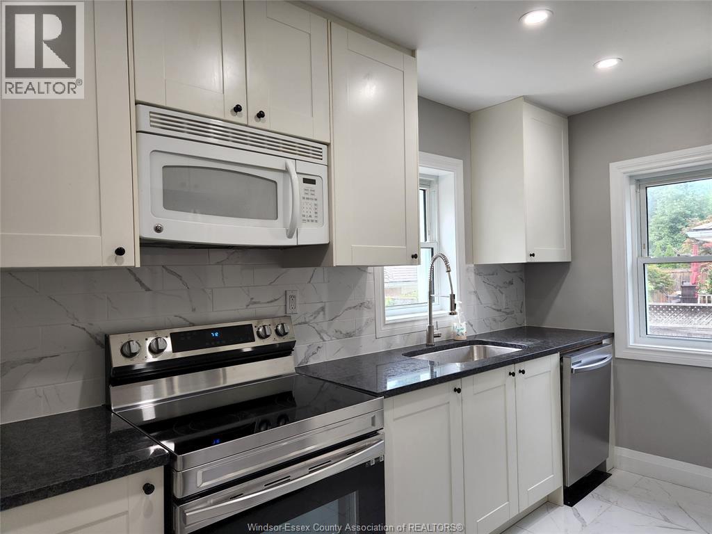A kitchen with white cabinets and black countertops.