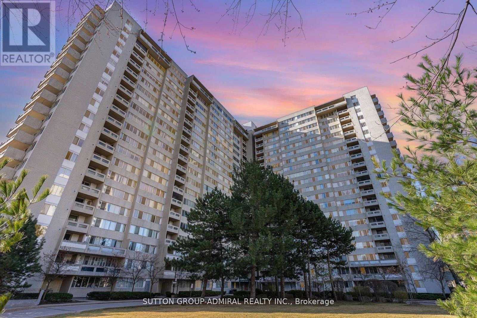 A tall residential building with a tree in front of it.