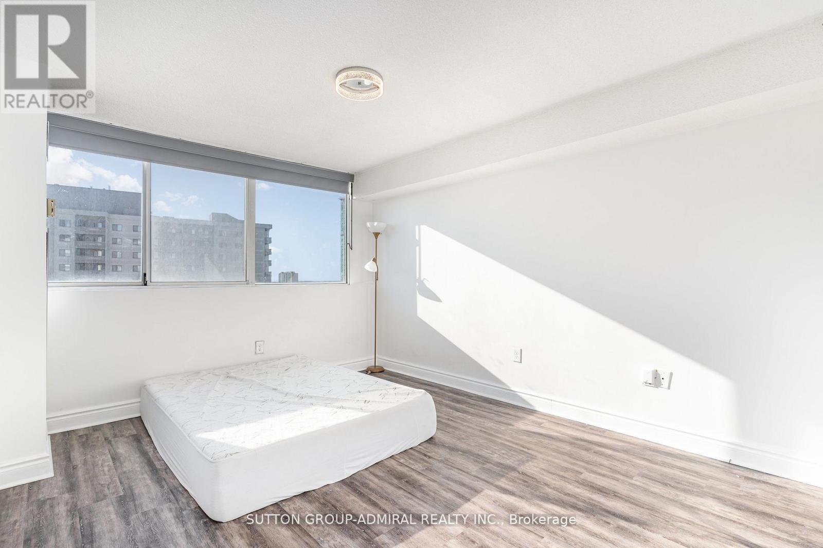 A bedroom with a large bed and a window overlooking a cityscape.