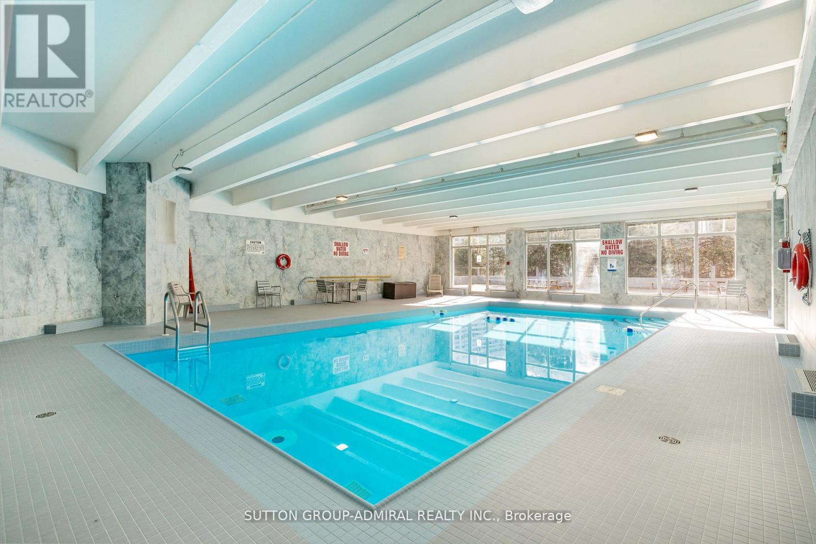 A large indoor swimming pool with a tiled floor and a stone wall.