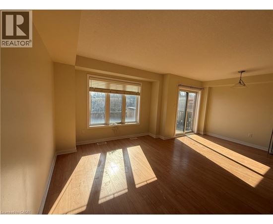 A sunny room with wooden floors and a large window.