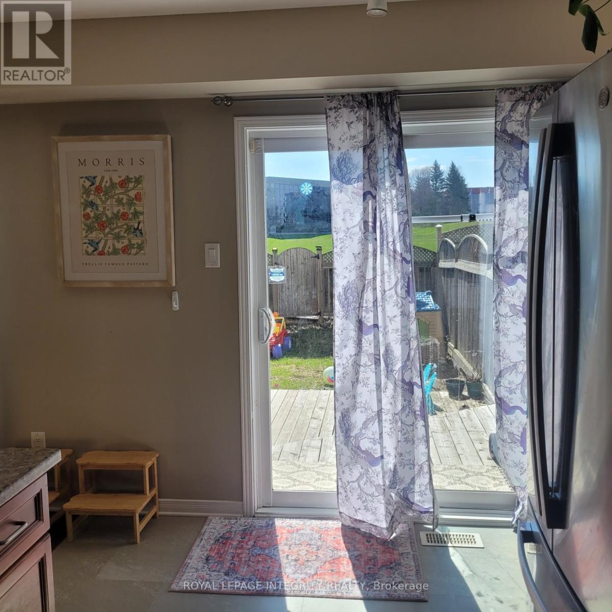 A kitchen with a fridge, a table and a window with curtains.