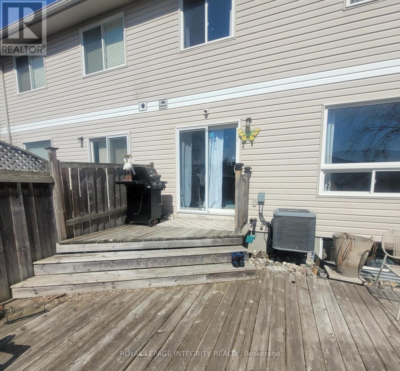 A wooden deck with a grill and a hot tub on it.