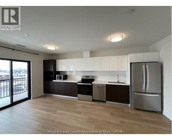 A kitchen with a refrigerator, sink, and microwave.
