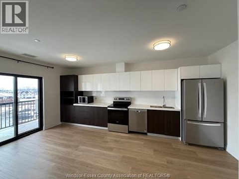 A kitchen with a refrigerator, sink, and microwave.