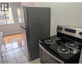 A black stove top oven with four burners and a silver refrigerator in a kitchen.