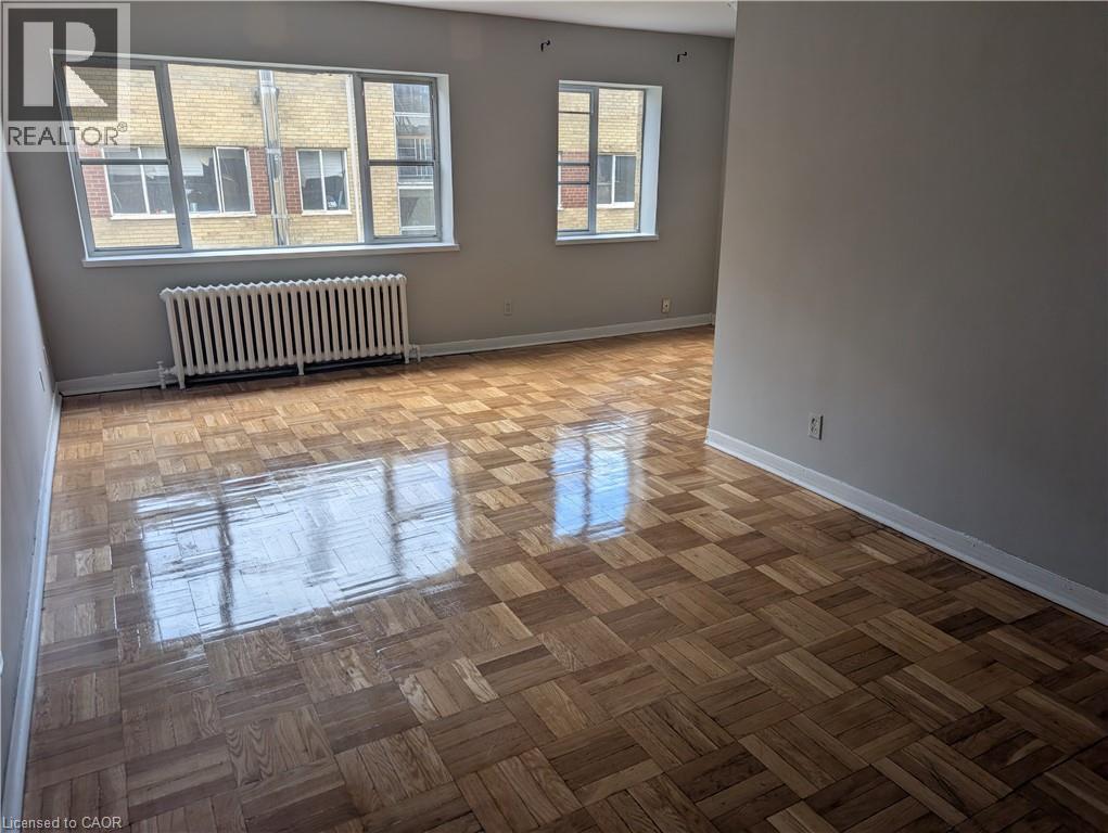 A room with wooden flooring and a window with a radiator beneath it.