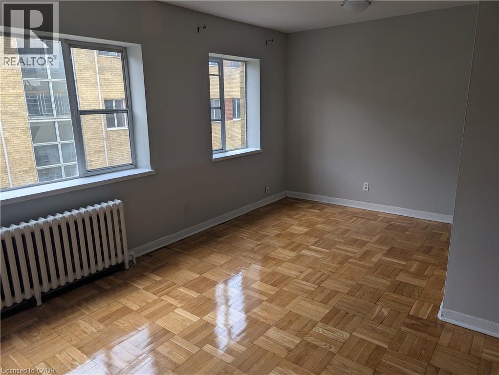 A room with wooden flooring and two windows.