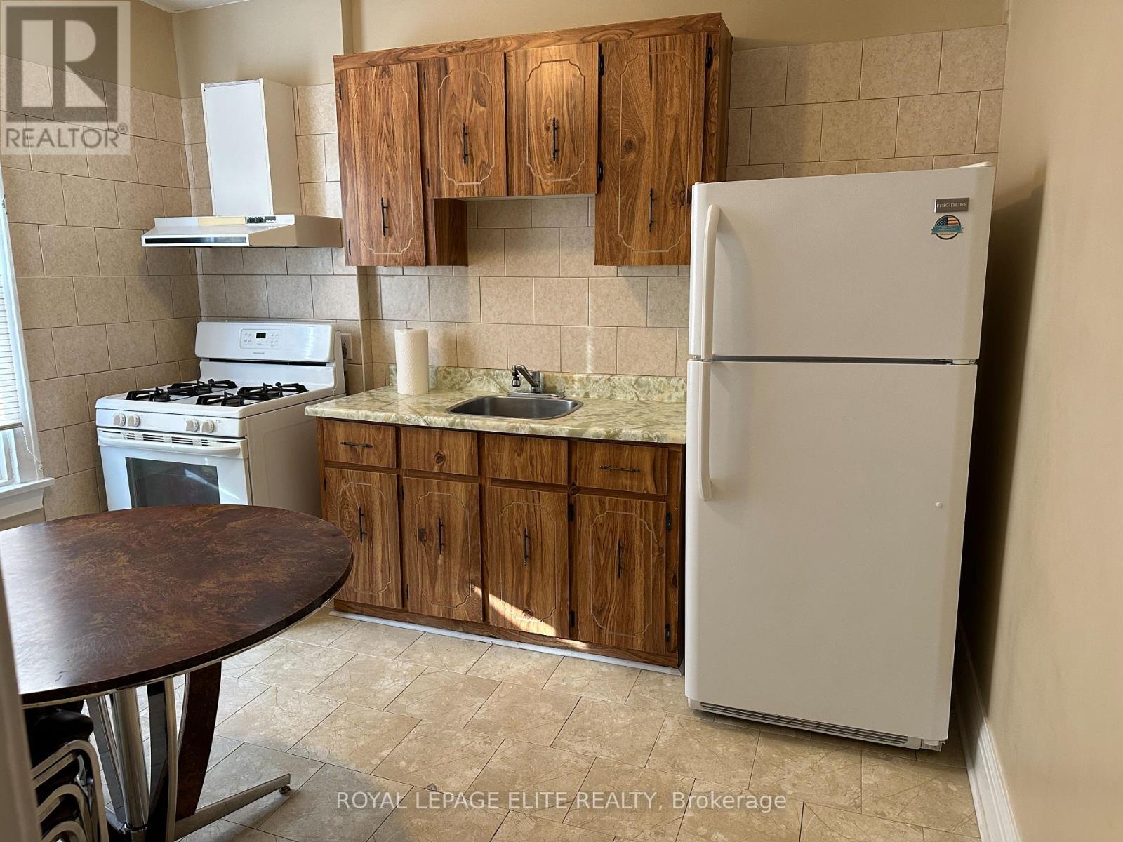 A kitchen with a white fridge, wooden cabinets and a tiled backsplash.