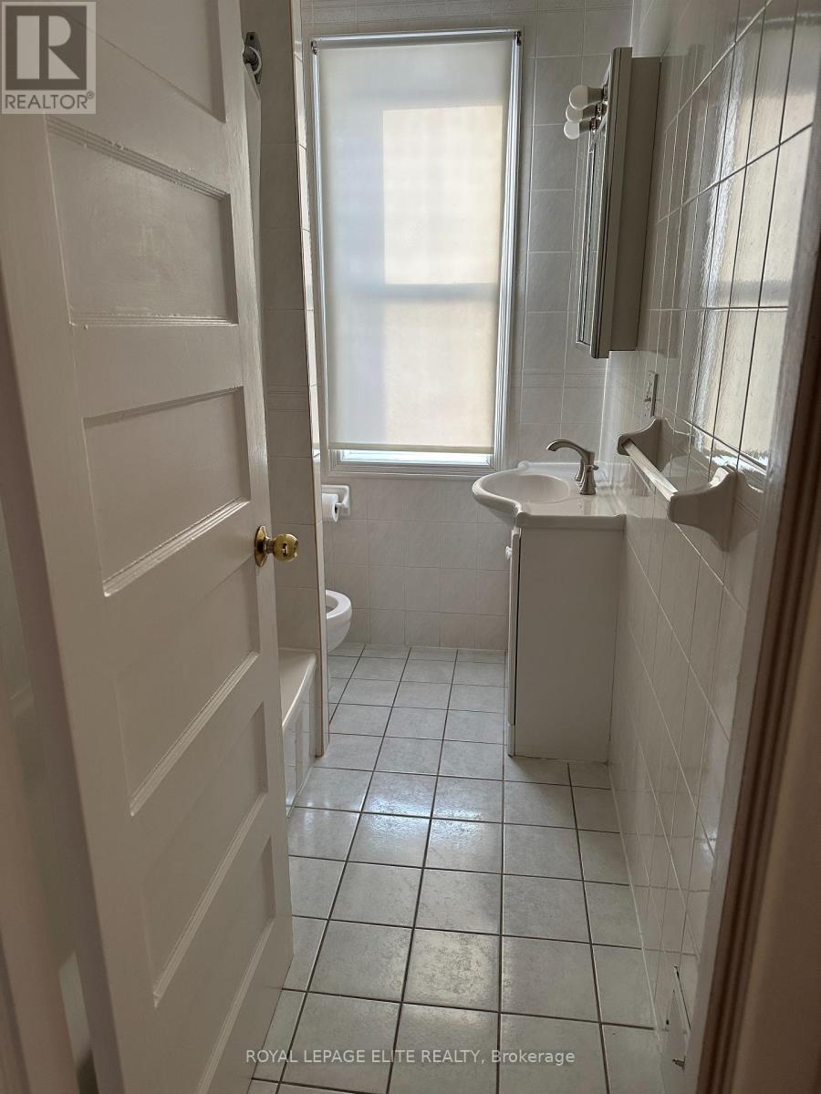 A white bathroom with a toilet, sink, and mirror.