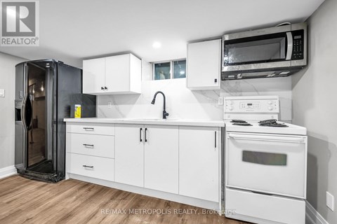 A white kitchen with a black fridge and a white oven.