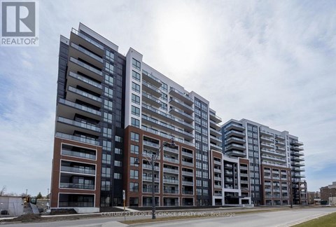 A large, modern apartment building with multiple balconies and a clear sky in the background.