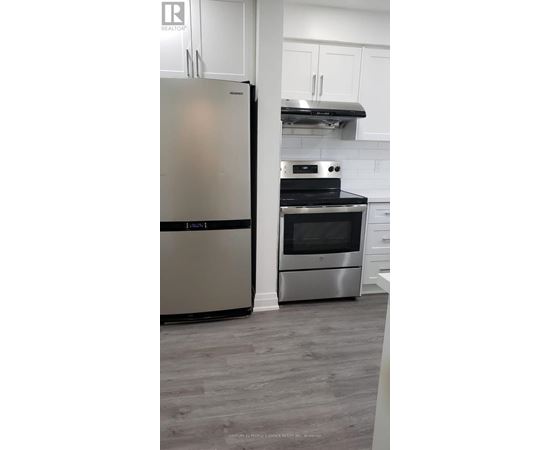 A modern kitchen with a stainless steel refrigerator and oven.