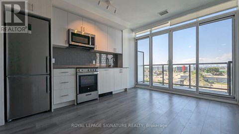 A kitchen with a refrigerator, oven, and microwave.