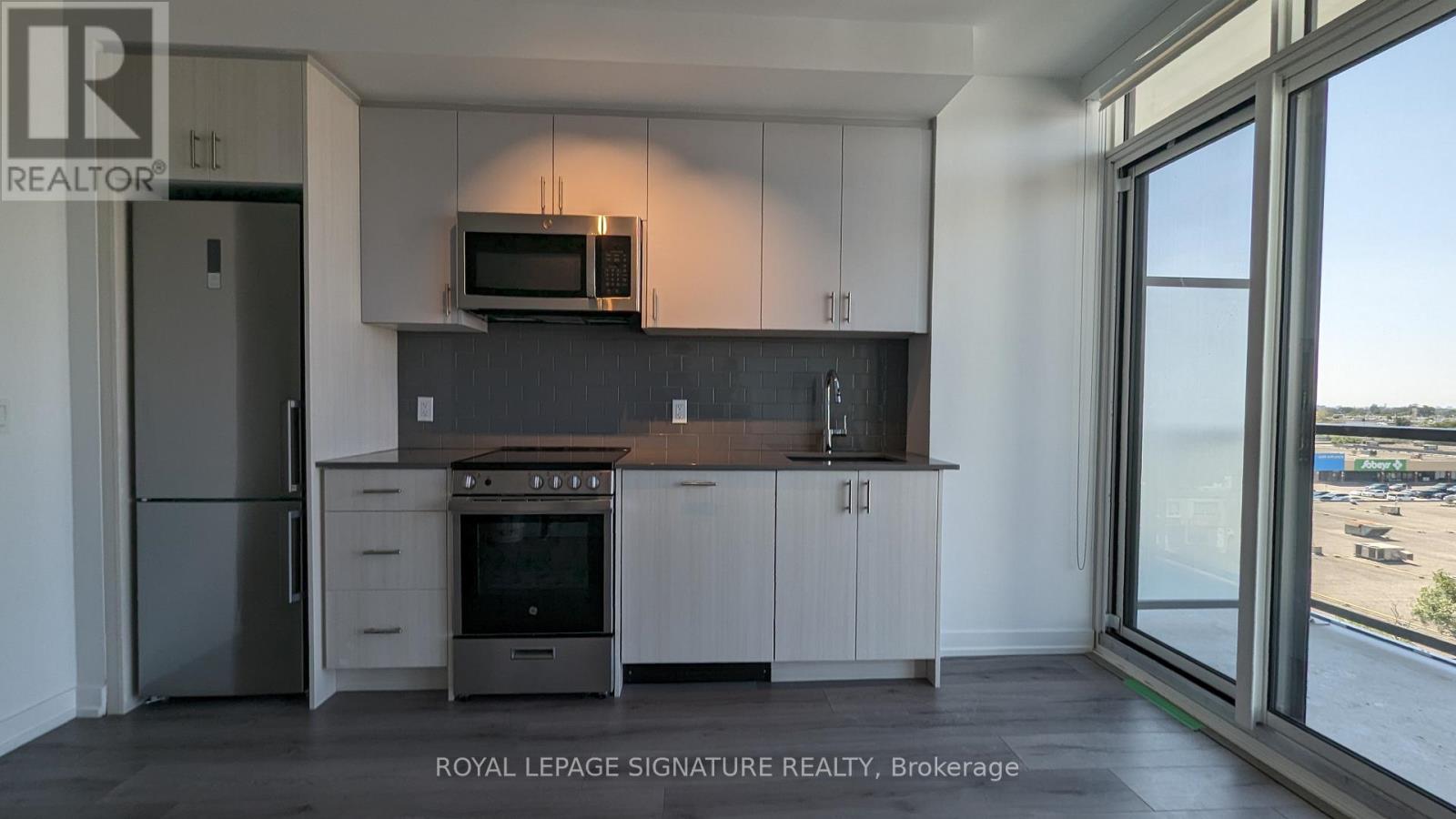 A kitchen with a refrigerator, oven, microwave, and cabinets.