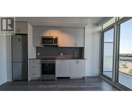 A kitchen with a refrigerator, oven, microwave, and cabinets.