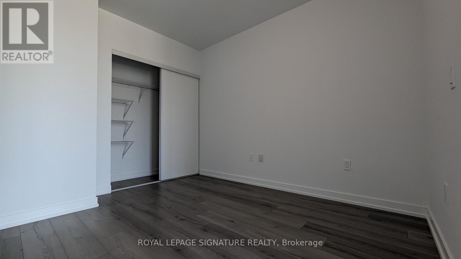 A room with a wooden floor and a white wall with a doorway.