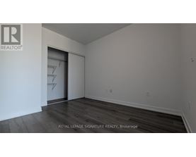 A room with a wooden floor and a white wall with a doorway.