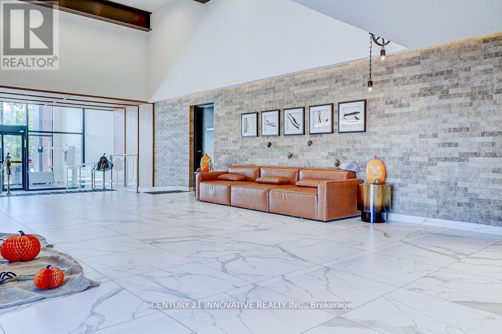 A living room with a brown leather couch and a grey stone wall.