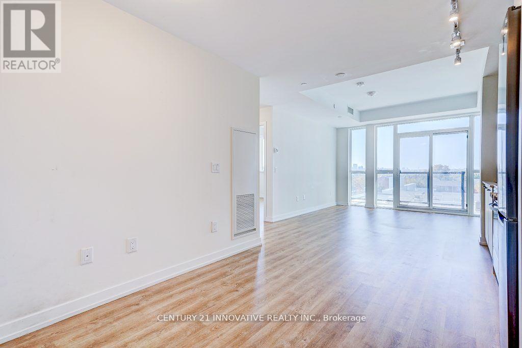 A spacious room with wooden flooring and a large window.