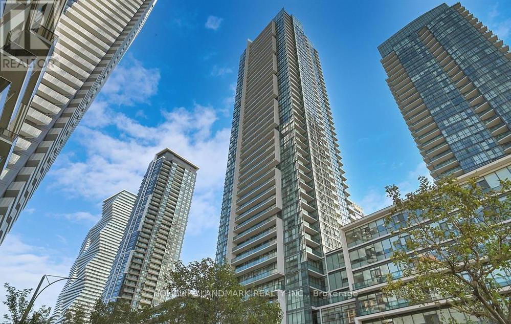 A tall building stands in front of other buildings on a sunny day.
