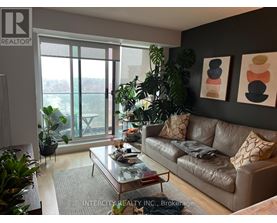 A living room with a couch, coffee table, and plants.
