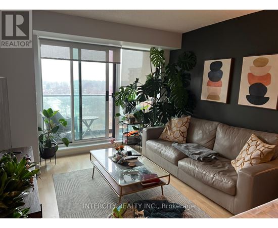 A living room with a couch, coffee table, and plants.