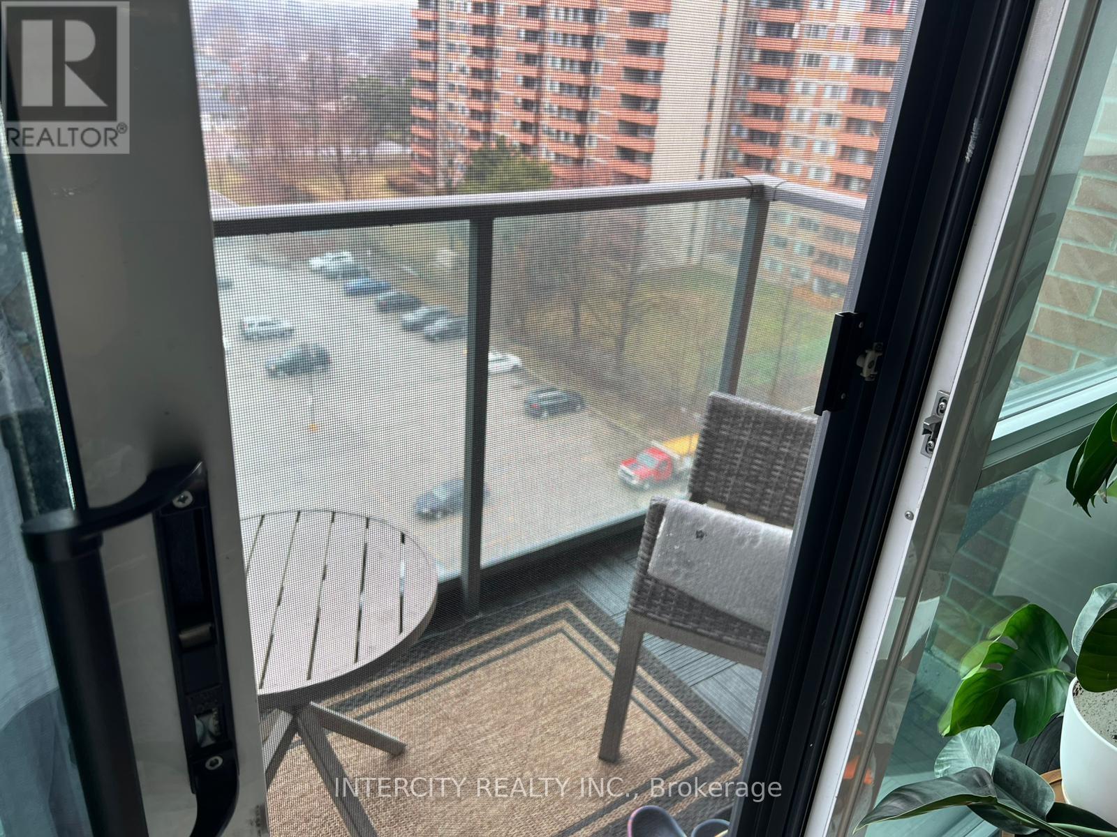 A balcony with a table and chairs overlooking a parking lot.
