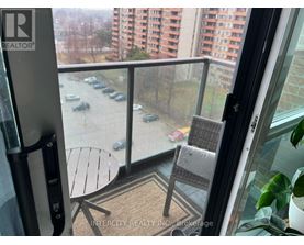 A balcony with a table and chairs overlooking a parking lot.