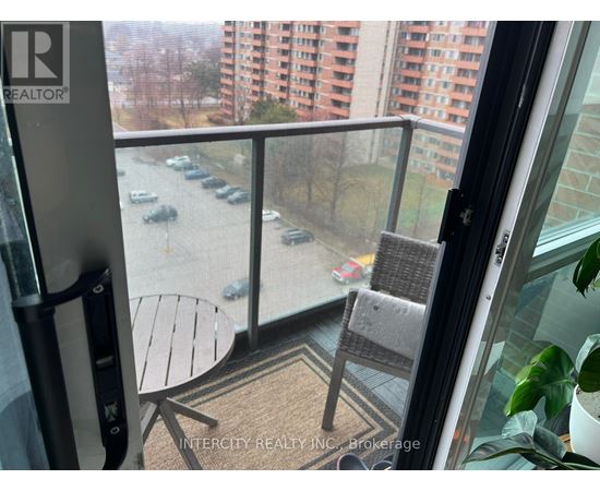 A balcony with a table and chairs overlooking a parking lot.