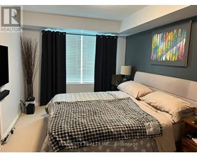 A bedroom with a bed, nightstand, and a painting on the wall.
