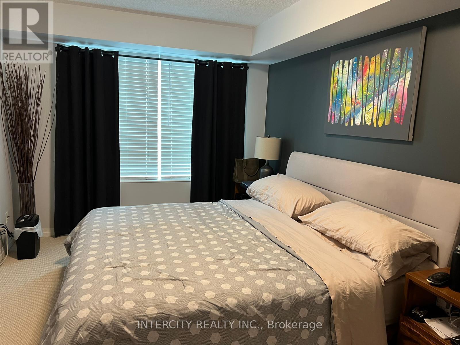 A bedroom with a large bed and a painting on the wall.