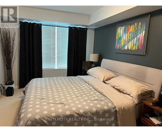 A bedroom with a large bed and a painting on the wall.