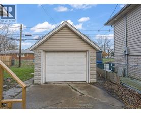 A detached garage with a white door is situated in a residential area.