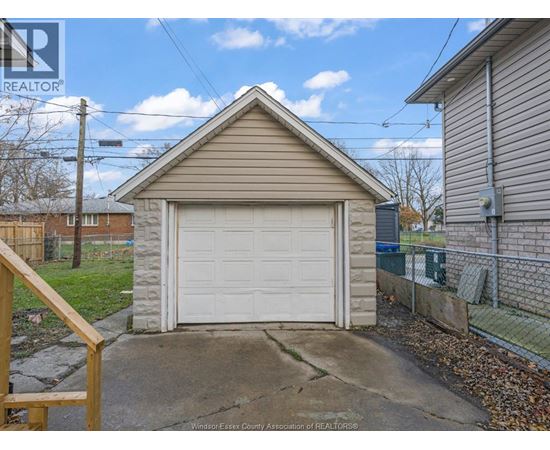 A detached garage with a white door is situated in a residential area.