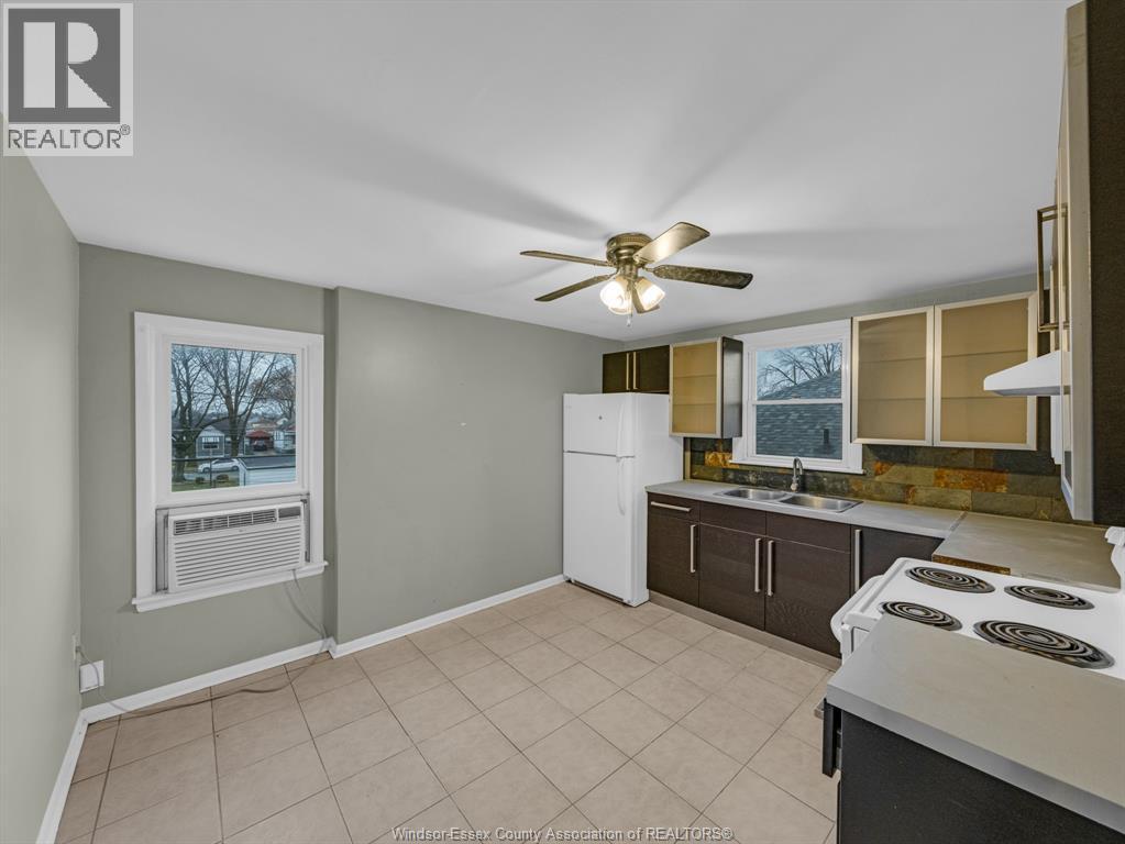 A kitchen with a white refrigerator and a fan on the ceiling.