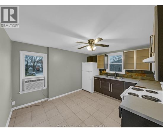 A kitchen with a white refrigerator and a fan on the ceiling.