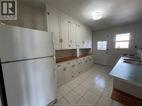 A kitchen with white cabinets and a white refrigerator.