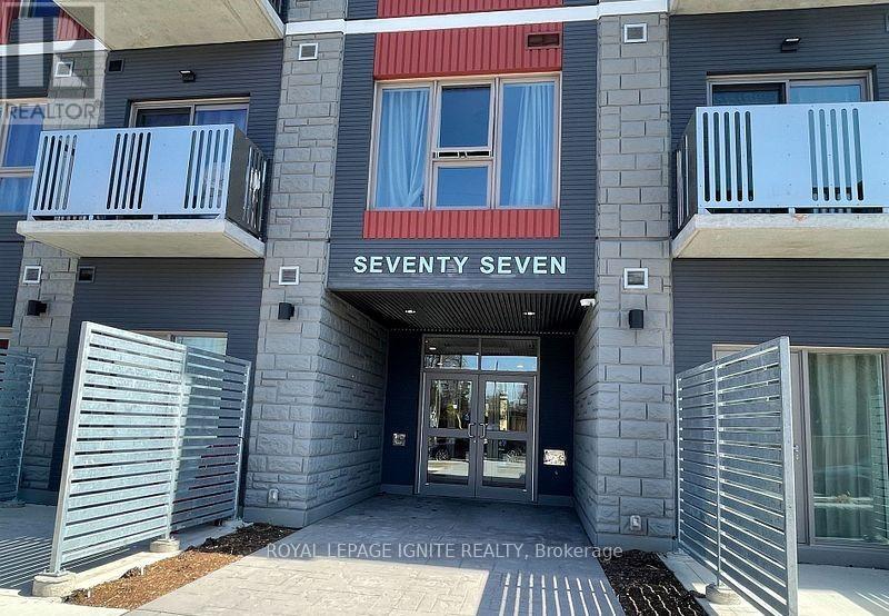 The entrance to a building named Seventy Seven with a glass door and a metal gate.