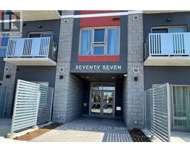 The entrance to a building named Seventy Seven with a glass door and a metal gate.