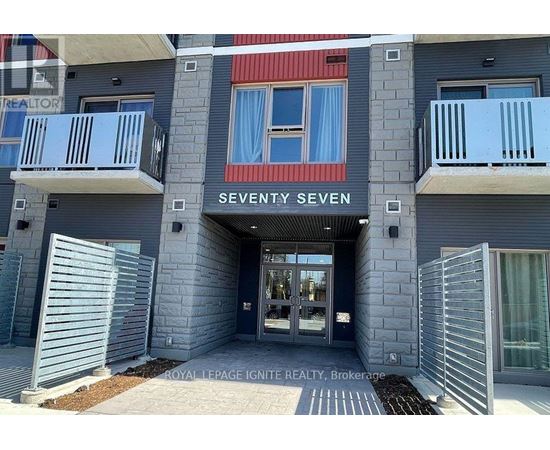 The entrance to a building named Seventy Seven with a glass door and a metal gate.
