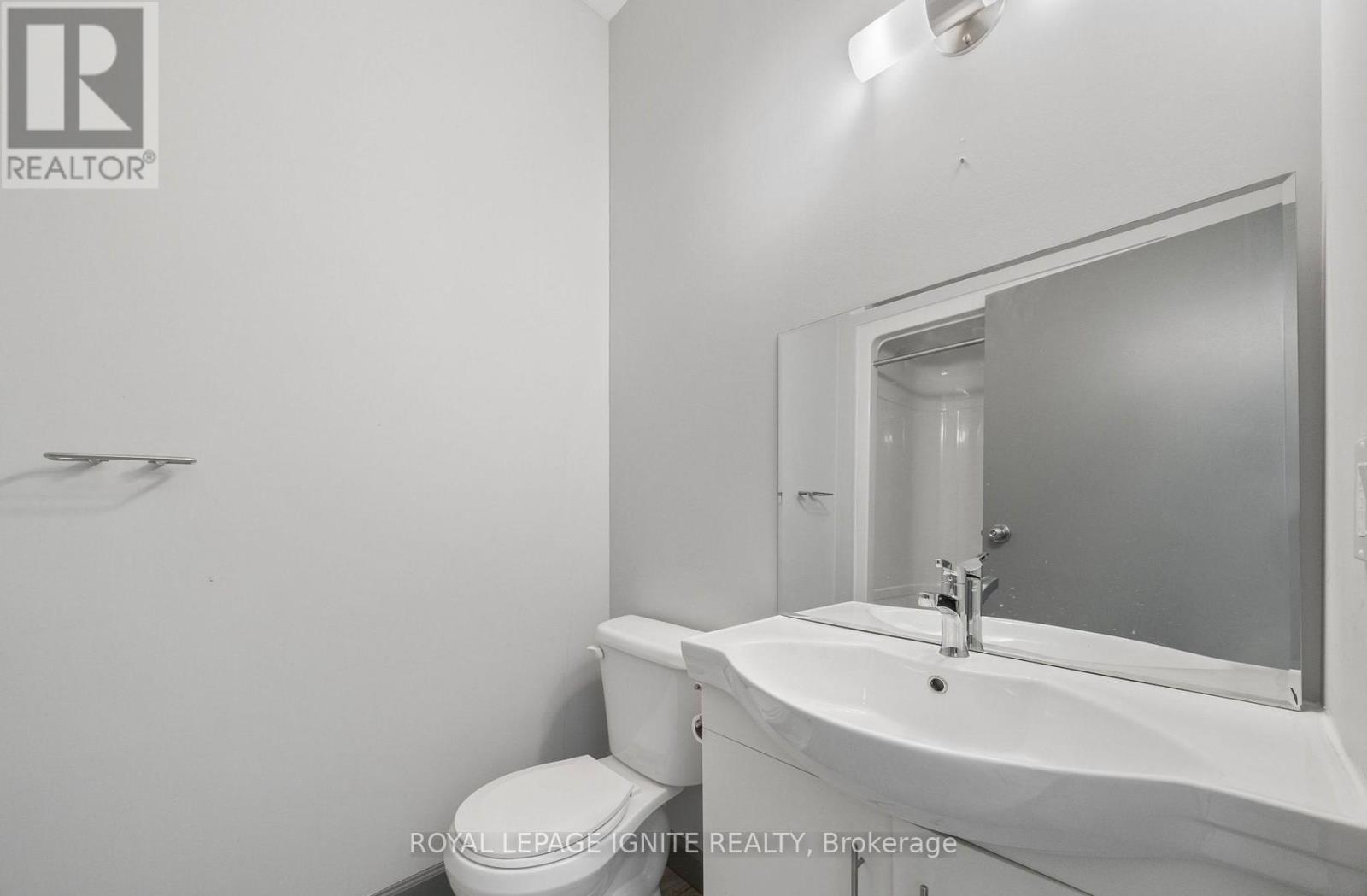 A white bathroom with a toilet, sink and mirror.