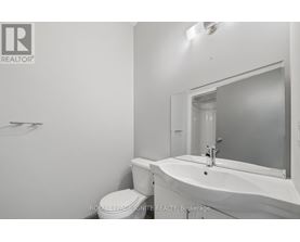 A white bathroom with a toilet, sink and mirror.