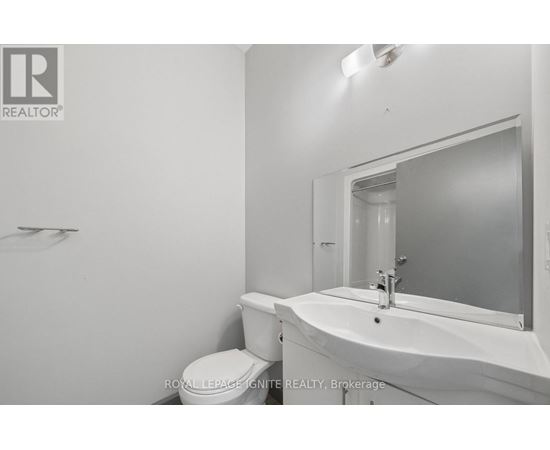 A white bathroom with a toilet, sink and mirror.
