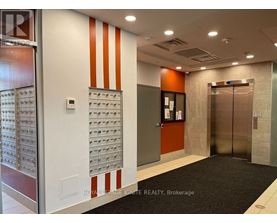 A hallway with a black carpet and a wall of mailboxes.