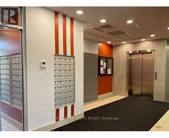 A hallway with a black carpet and a wall of mailboxes.