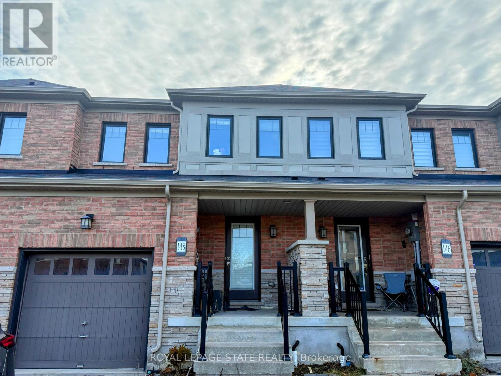 A house with a brick facade and a garage door is for sale.