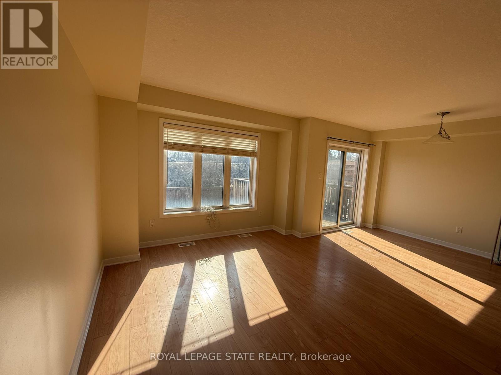 A sunny room with wooden floors and a large window.